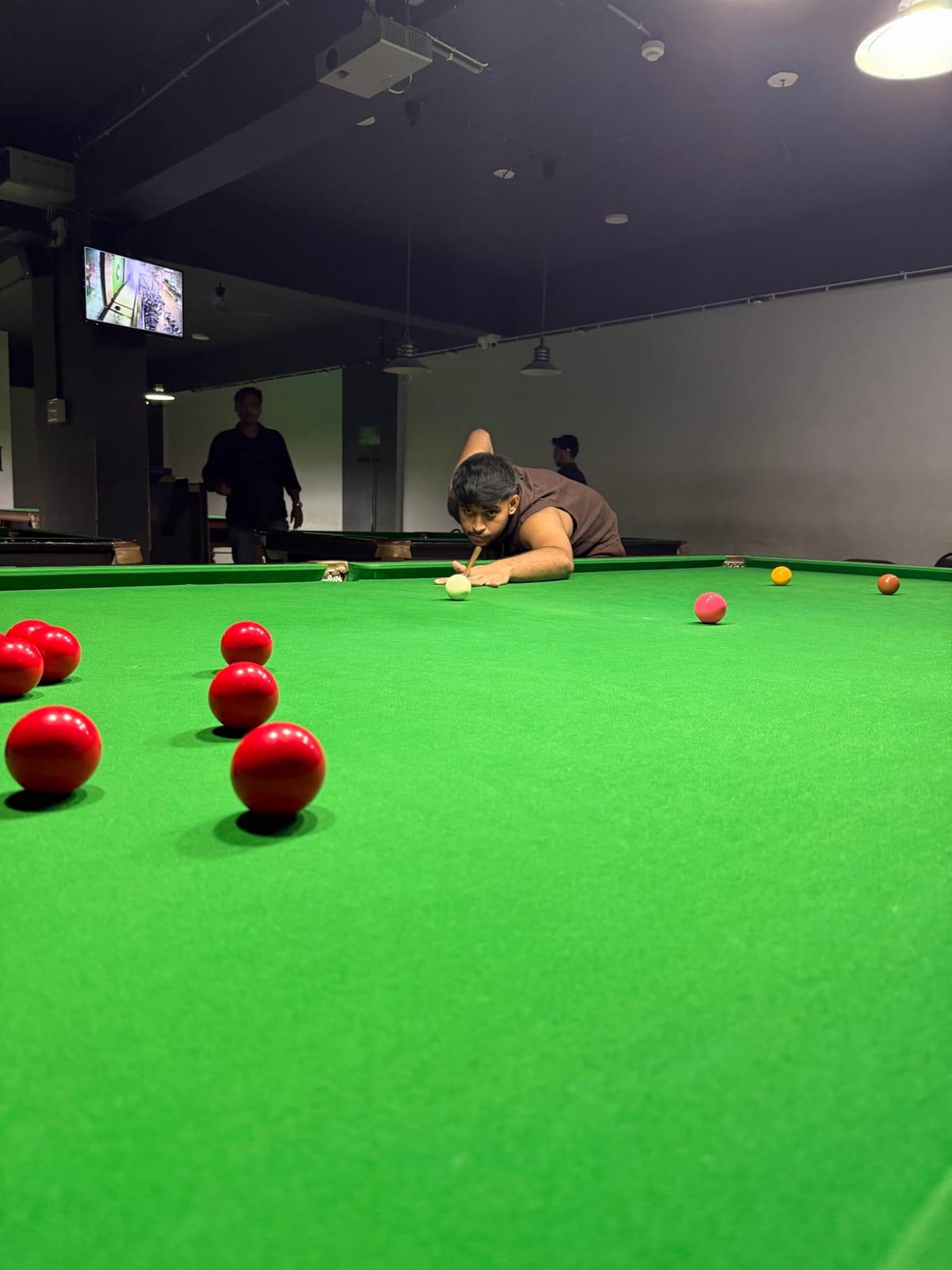 A player at eye level with the cue ball, reading the table before his next shot
